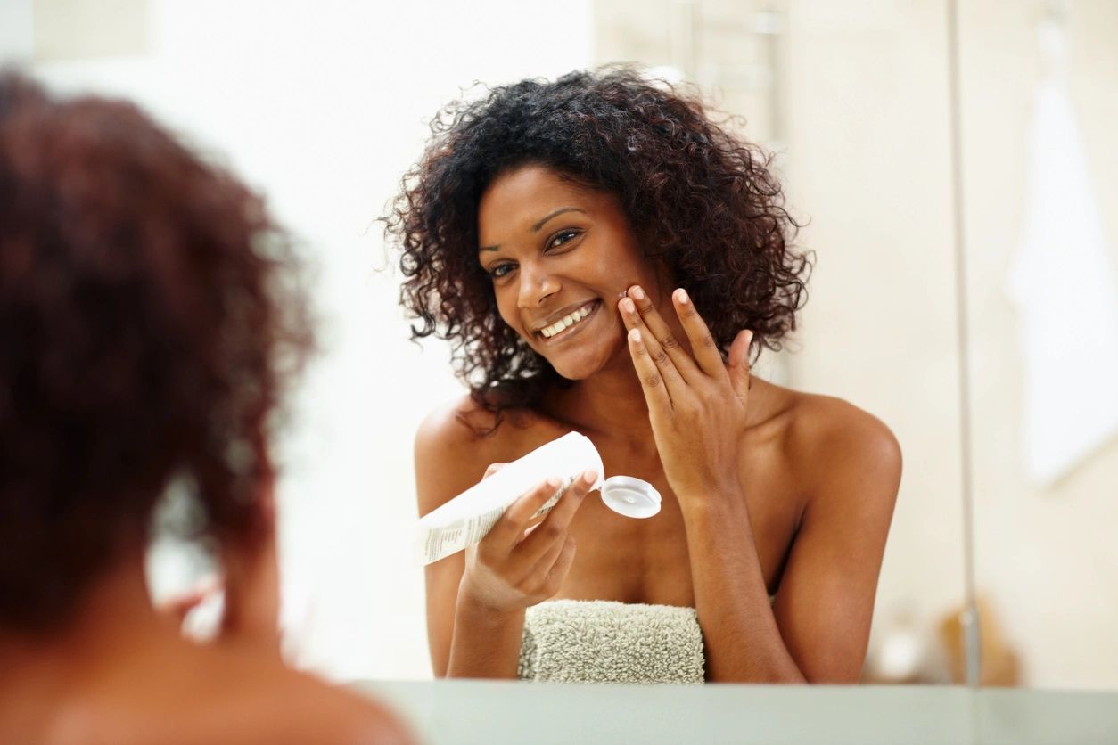 An adult woman putting on a skin care product